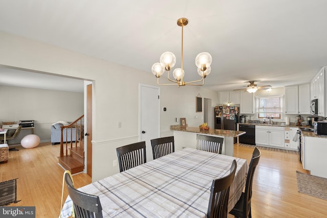 dining room featuring ceiling fan with notable chandelier, stairs, and light wood finished floors