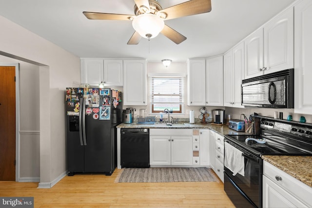 kitchen with light stone countertops, a sink, light wood-type flooring, black appliances, and white cabinetry