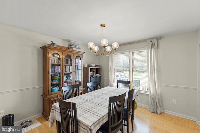 dining space featuring baseboards, a notable chandelier, and light wood finished floors