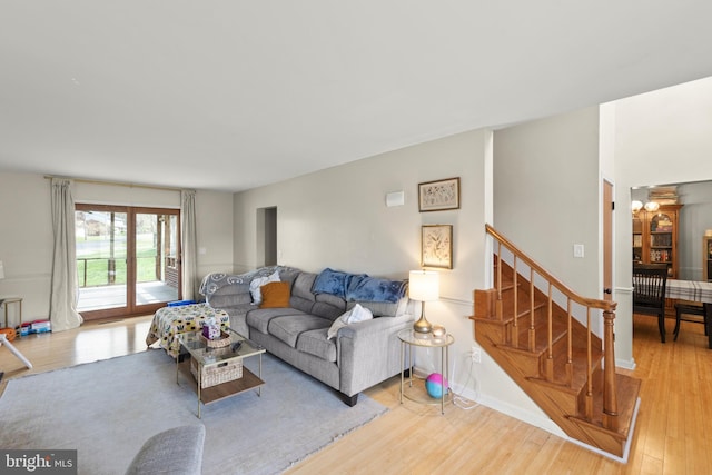 living area with stairs, baseboards, and light wood-type flooring