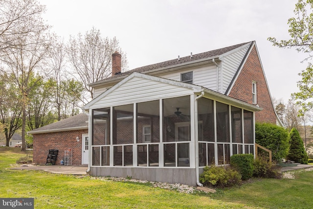 rear view of property featuring a sunroom, a lawn, a patio area, and a chimney