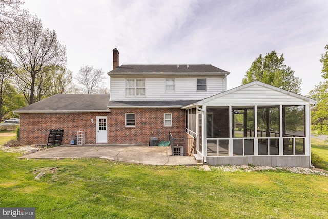 back of property with a sunroom, brick siding, a patio area, a yard, and a chimney