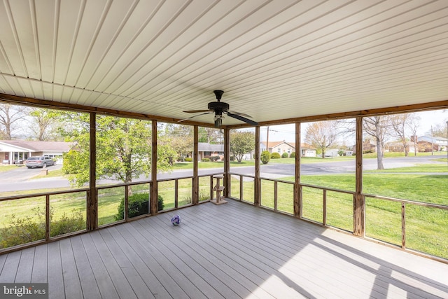unfurnished sunroom with a ceiling fan and a residential view