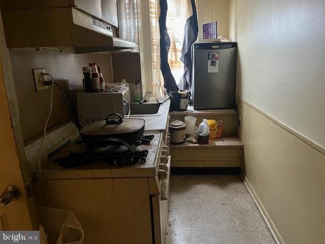 4900 N 11th St, Philadelphia, PA 19141 - kitchen with baseboards, under cabinet range hood, water heater, tile counters, and white range with gas stovetop