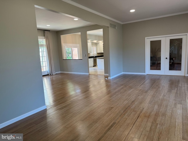 unfurnished living room with french doors, baseboards, wood finished floors, and visible vents