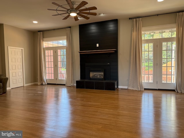 unfurnished living room featuring a tiled fireplace, recessed lighting, baseboards, a ceiling fan, and wood finished floors