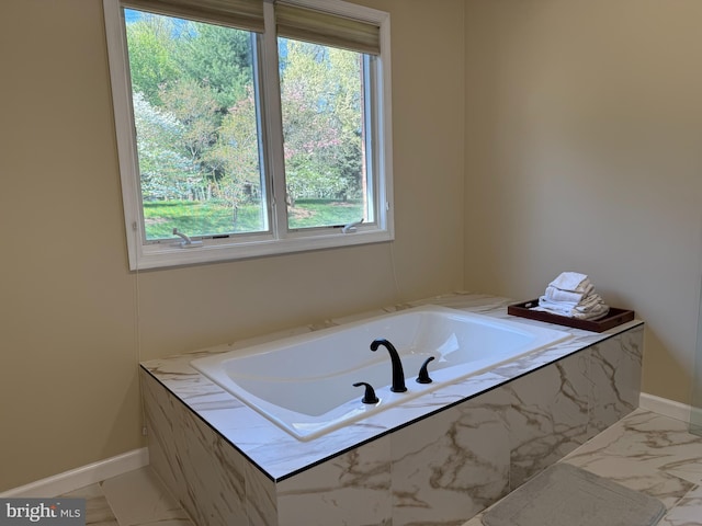 bathroom featuring baseboards, a garden tub, and marble finish floor