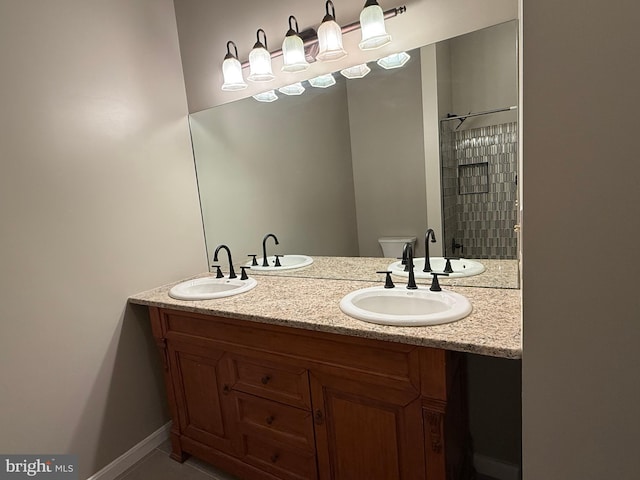 bathroom featuring double vanity, a sink, a tile shower, and toilet