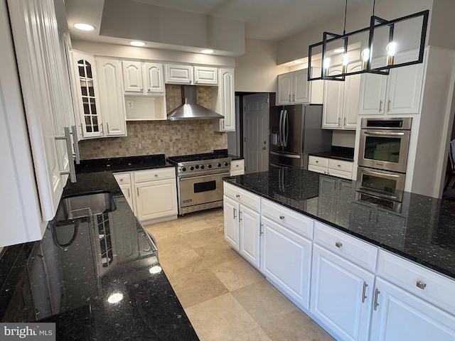 kitchen featuring white cabinetry, appliances with stainless steel finishes, wall chimney range hood, and tasteful backsplash