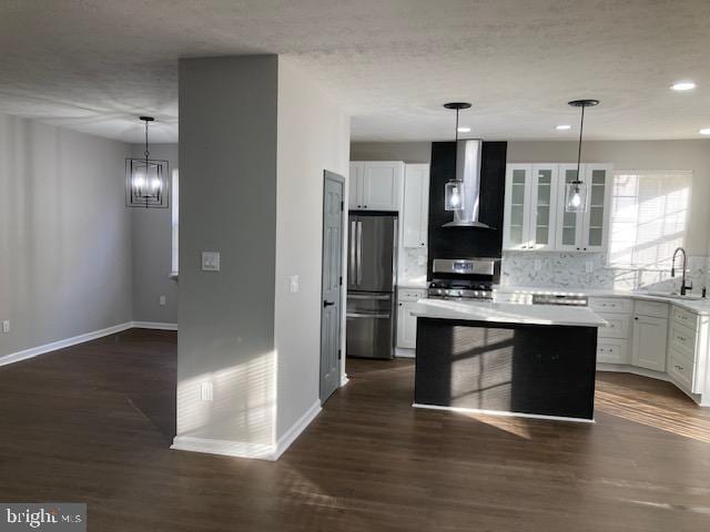 kitchen with white cabinets, dark wood-style floors, baseboards, wall chimney range hood, and appliances with stainless steel finishes