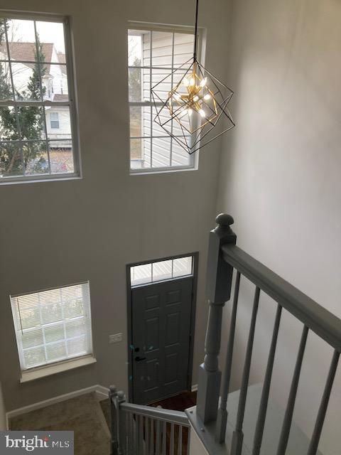 foyer entrance with stairway, an inviting chandelier, and a high ceiling