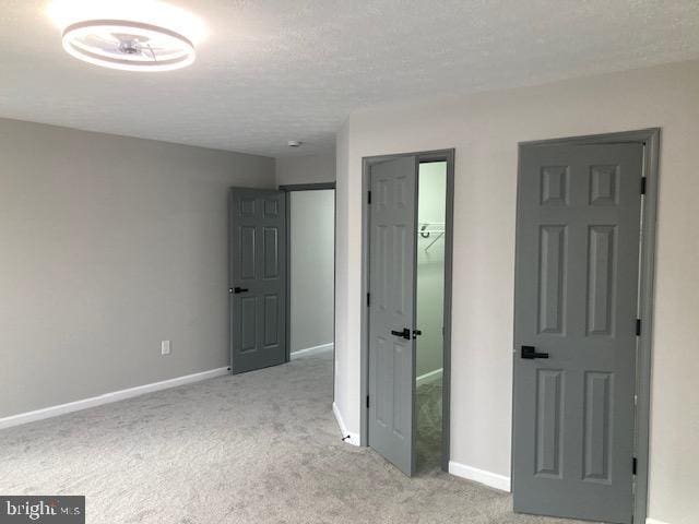 unfurnished bedroom featuring carpet floors, a textured ceiling, and baseboards
