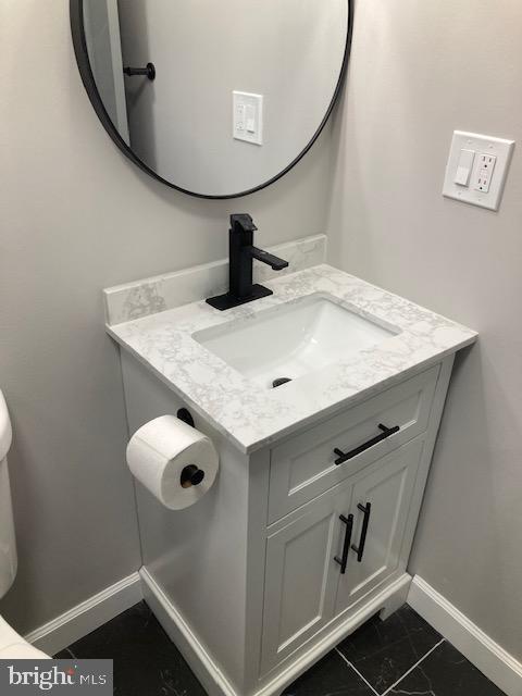 half bath featuring baseboards and vanity
