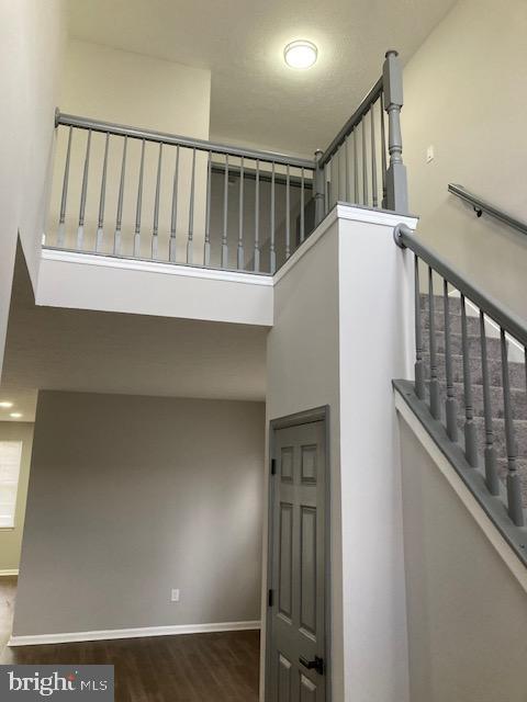 stairs with baseboards, wood finished floors, and a towering ceiling