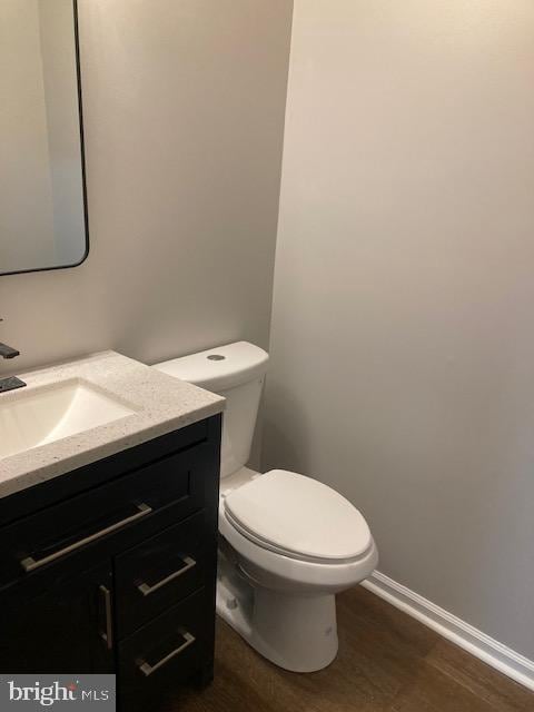 bathroom with baseboards, wood finished floors, toilet, and vanity