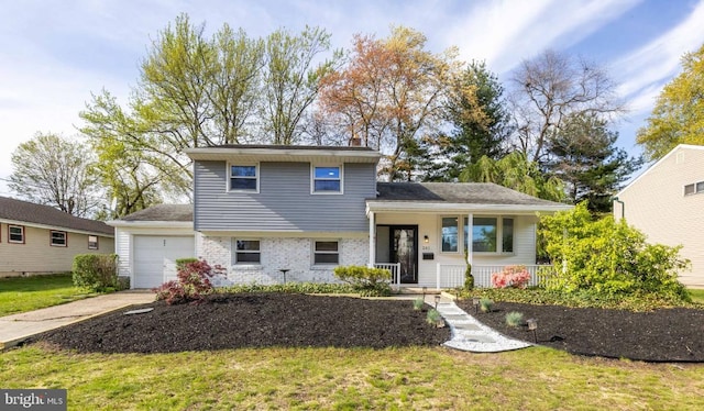split level home with concrete driveway, covered porch, a garage, brick siding, and a front yard