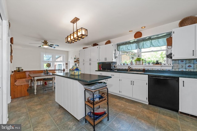 kitchen with dark countertops, a sink, a healthy amount of sunlight, and dishwasher