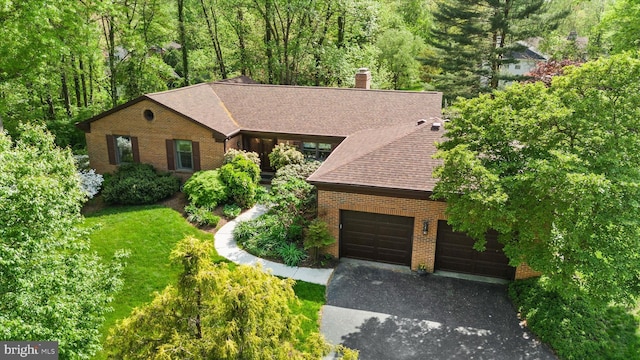 view of front of property featuring a chimney, brick siding, a shingled roof, an attached garage, and driveway