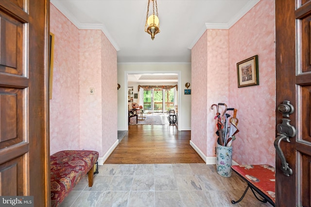 foyer entrance featuring crown molding, baseboards, and stone finish flooring