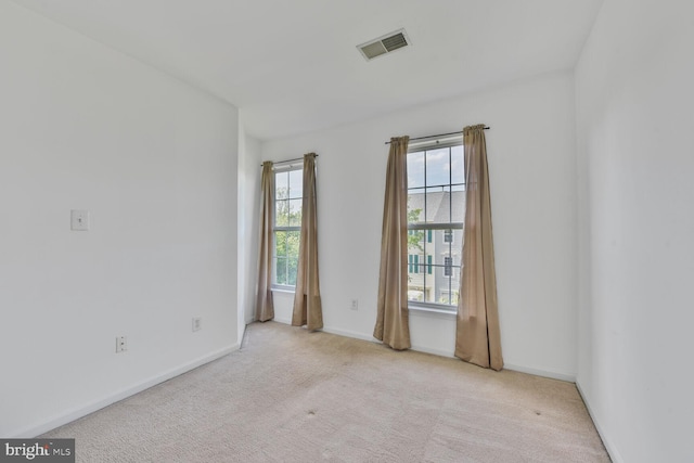 empty room with a wealth of natural light, carpet, and visible vents