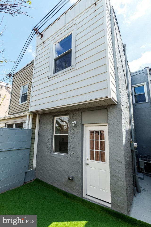 rear view of house with stucco siding, fence, and central AC