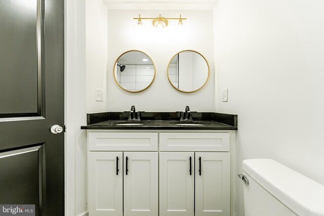 full bathroom featuring toilet, a sink, and double vanity
