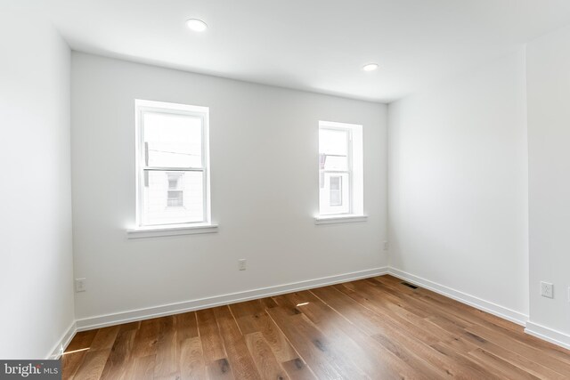 empty room featuring baseboards, wood finished floors, visible vents, and recessed lighting