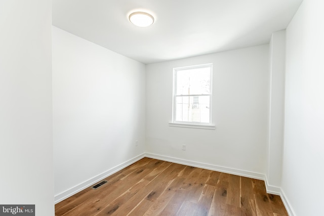 empty room featuring hardwood / wood-style flooring, baseboards, and visible vents