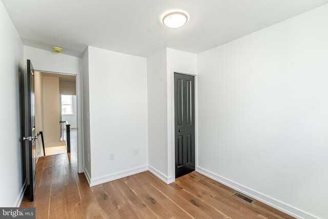 unfurnished bedroom with baseboards, wood finished floors, visible vents, and a closet