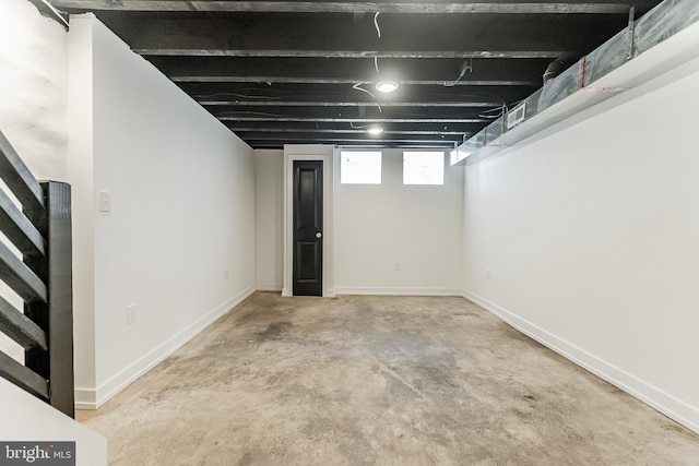 basement featuring baseboards and stairs