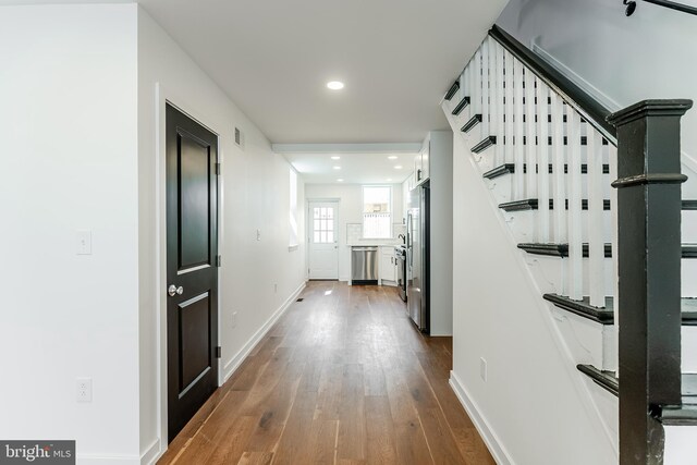 corridor with baseboards, recessed lighting, stairway, and dark wood-style flooring