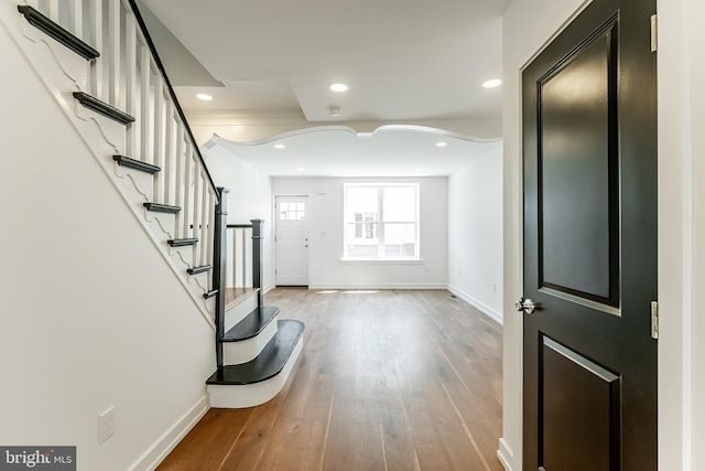 foyer entrance featuring baseboards, wood finished floors, and recessed lighting