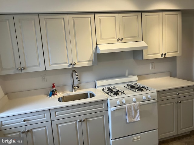 kitchen featuring a sink, gray cabinetry, white gas stove, and under cabinet range hood