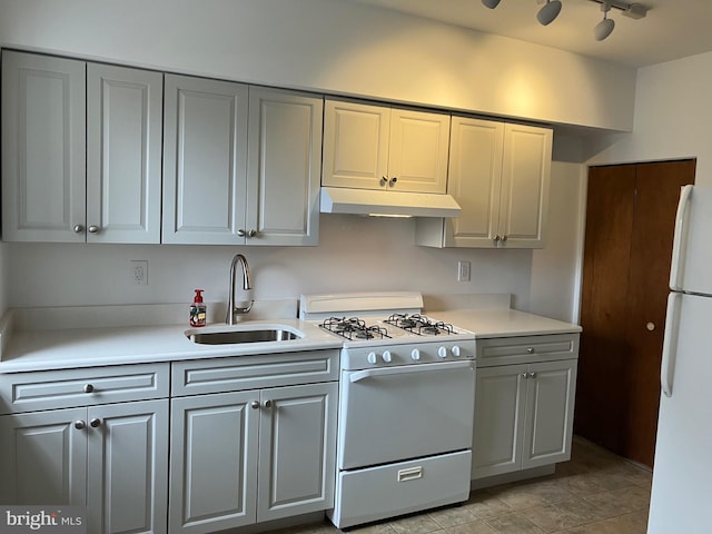 kitchen with gray cabinets, a sink, light countertops, under cabinet range hood, and white appliances