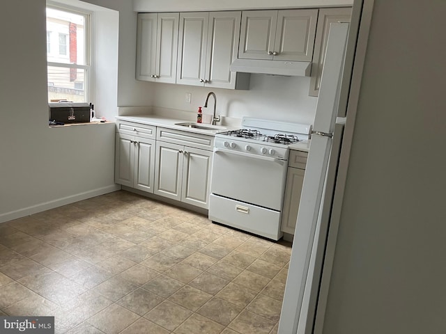 kitchen featuring a sink, light countertops, white gas range oven, baseboards, and under cabinet range hood