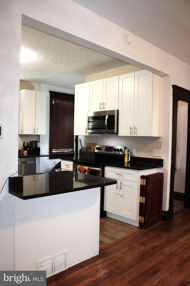 408 Prince George St, Cumberland, MD 21502 - kitchen featuring stainless steel appliances, dark countertops, white cabinetry, and dark wood-type flooring