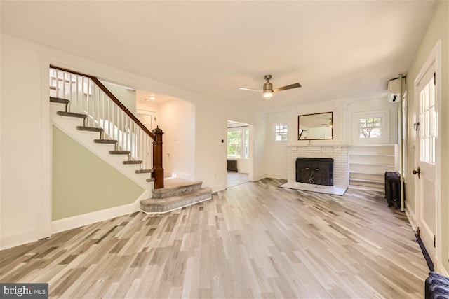 105 E Maple Rd, Linthicum Heights, MD 21090 - unfurnished living room with stairs, ceiling fan, a brick fireplace, baseboards, and light wood-type flooring