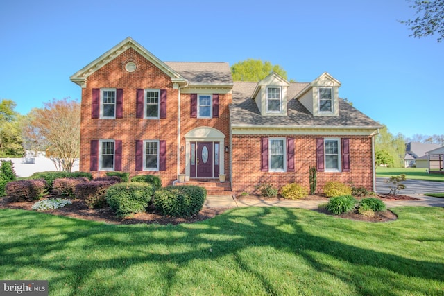 view of front facade with brick siding and a front yard