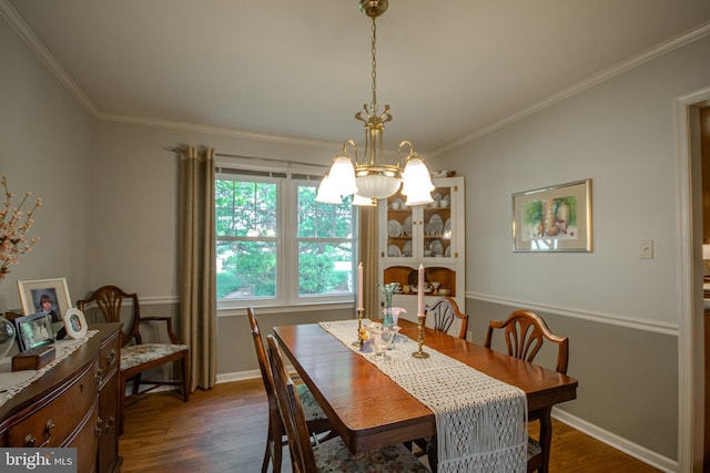 dining space featuring an inviting chandelier, crown molding, baseboards, and dark wood finished floors