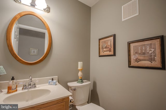 half bathroom with vanity, toilet, and visible vents