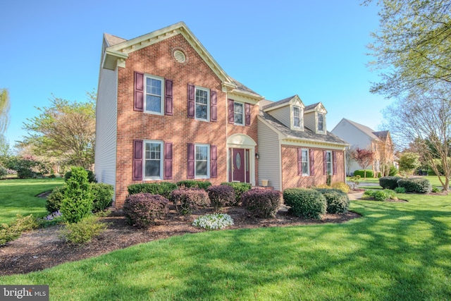 traditional home featuring a front yard and brick siding