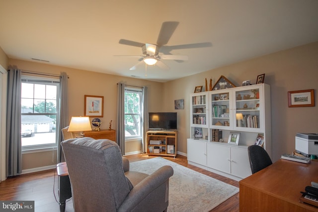 living room with baseboards, a ceiling fan, visible vents, and wood finished floors
