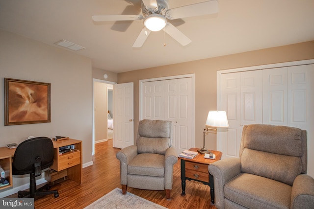 sitting room featuring a ceiling fan, baseboards, visible vents, and wood finished floors
