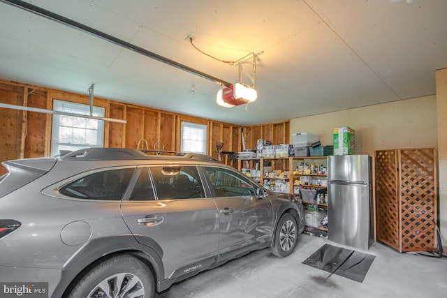 garage with freestanding refrigerator, wooden walls, and a garage door opener