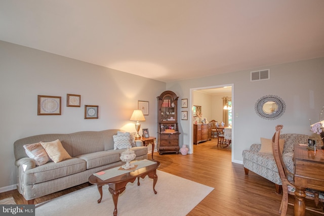living room featuring baseboards, visible vents, and wood finished floors