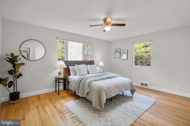bedroom with baseboards, wood finished floors, and visible vents