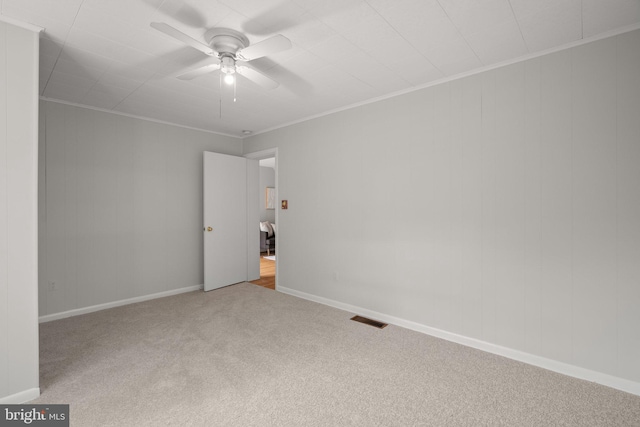 carpeted empty room featuring baseboards, ceiling fan, ornamental molding, and visible vents