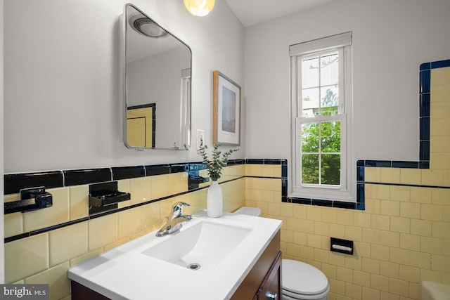 bathroom with toilet, tile walls, a healthy amount of sunlight, and vanity