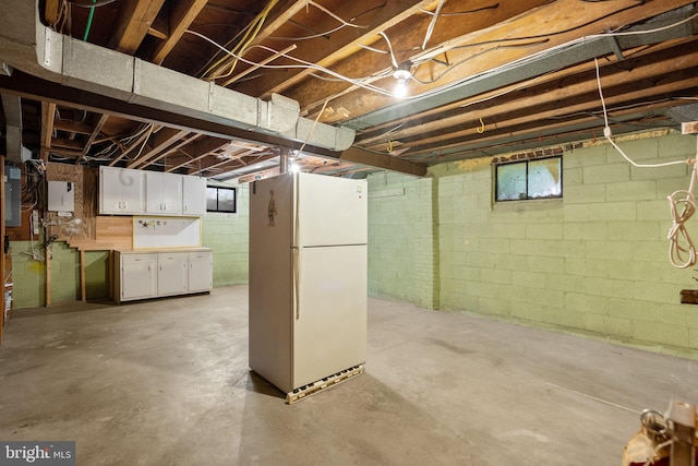 below grade area featuring freestanding refrigerator and electric panel