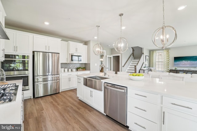kitchen featuring a sink, an inviting chandelier, decorative backsplash, light countertops, and appliances with stainless steel finishes